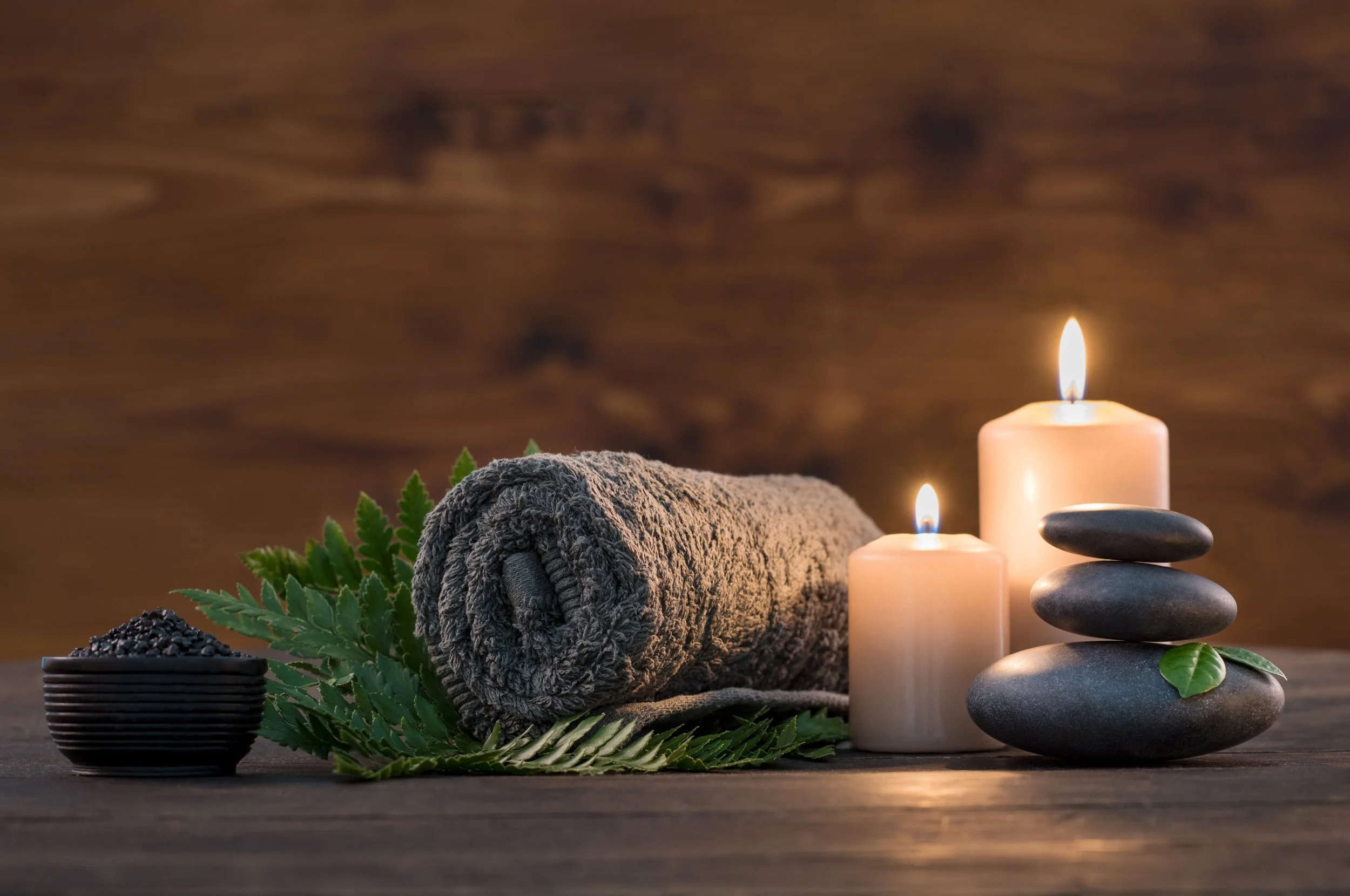 Rolled towel, candles and smooth stones in a spa treatment room